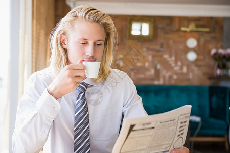男人在看报纸时喝咖啡阅读闲暇智能餐厅咖啡酒店男性金发女郎休息杯子背景图片