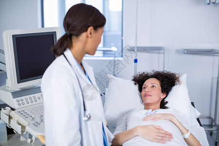 医生在做超声波扫描时与孕妇进行交互接触母性互动医院医务室病床专家医学诊所保健孕妇装背景图片