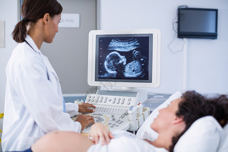 为孕妇进行超声波扫描的医生实验室专家指导怀孕住院医师腹部体格机器放射科背景