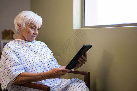 高级病人持有数字平板电脑医院病号闲暇智力网络女士技术触摸屏阅读童年背景图片