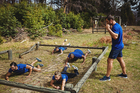 适合在障碍课程期间爬到网下的人军事军营女性挑战运动员娱乐训练营木头耐力生活方式背景图片