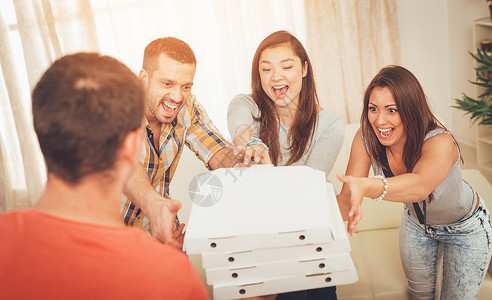 披萨晚会时间水平四个人乐趣选择性焦点女性微笑朋友们享受男生背景图片