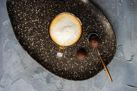 清晨杯卡布西诺石头黑色咖啡银器刀具牛奶杯子水泥桌子卡片背景图片