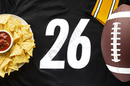 碗平视一个美国足球 配有有机玉米片和 白色黑色球衣上的轻度萨尔萨 26个数字在水平视线上背景