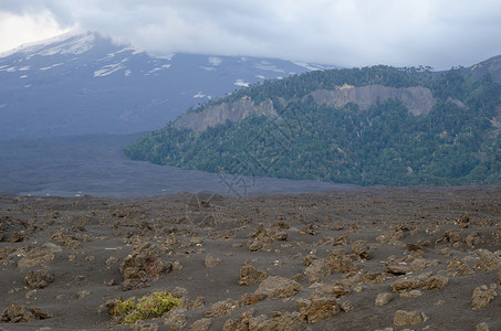 风景是你怎样都好坚固的熔岩和Llaima火山田 周围都是背景中的云层背景
