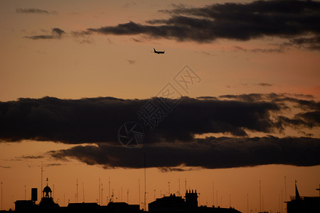 日落时空飞机穿越城市云层背景图片