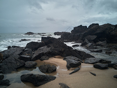 灰蒙蒙暴风雨过后海滩上的岩石飓风海景地标海岸线风景天空蓝色冲浪风暴海湾背景