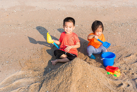 哥哥和妹妹两个孩子玩挖沙子玩玩具的滑稽挖掘弟兄们女孩帽子快乐姐姐热带活动闲暇幸福童年背景图片