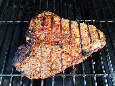 牛肉牛排和烧烤炉上的骨头牛肉炙烤午餐金属分数烹饪烧烤条纹痕迹美味背景图片