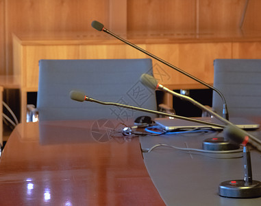 木制桌上的麦克风和会议室中的空椅子研讨会说话俱乐部扬声器集会讲台报告桌子演讲座位背景图片