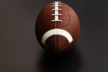孤立在黑色背景上的美式足球 运动对象 c猪皮皮革场地橄榄球硬木比赛娱乐阴影接缝聚光灯背景图片