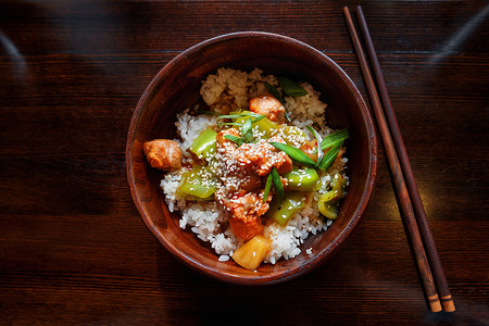 亚洲美食     炒蔬菜 菠萝和鲑鱼的酱汁大米有筷子的木质碗油炸盘子竹子芝麻烹饪乡村背景图片