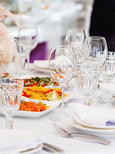 用餐具和花瓶里的鲜花 做婚礼宴席的餐桌 面条彩色装饰品派对桌子玻璃主菜餐厅盘子作品小吃褐色宴会背景图片