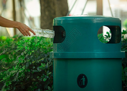 绿色废料人们手把空水瓶扔在公园的回收箱里背景