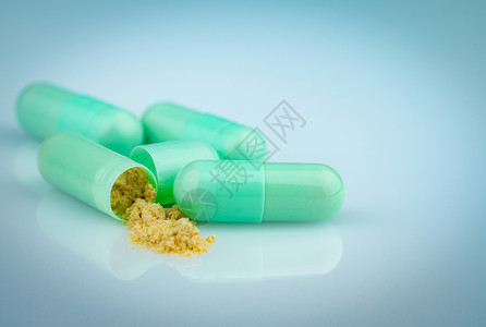 一组绿色胶囊 打开一个胶囊显示黄色粉末禁忌症药片商业处方市场法律反抗产品药物交易背景图片