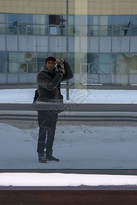 一个男人在冬日街道上的玻璃反射中自拍背景图片