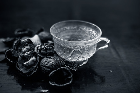 一个透明的玻璃杯里 紧贴着壁果或胡桃茶的草药有机茶 外壳上还有生墙坚果材料桌子杯子沙棘木板死角创造力八角蜂蜜乡村背景图片