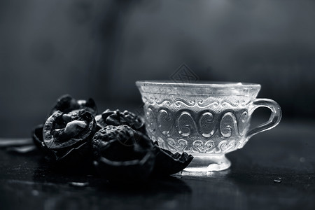 一个透明的玻璃杯里 紧贴着壁果或胡桃茶的草药有机茶 外壳上还有生墙坚果沙棘杯子厨房木板饮料甜点死角织物肉桂桌子背景图片