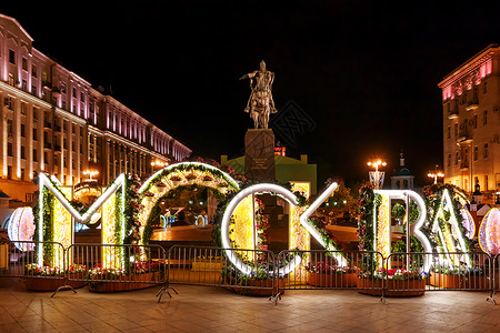 莫斯科夜景 莫斯科创始人王子的纪念碑 位于 Tverskaya 广场 发光字母“Moscow”上的花卉装饰背景图片