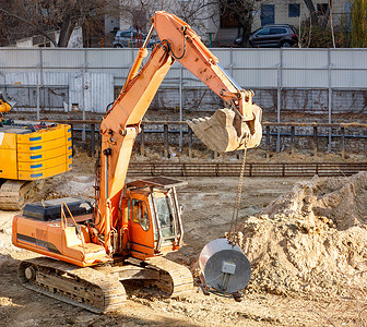 战壕城区住宅楼中一个有围栏的建筑工地上建造了一个重型爬行式挖土机工程项目背景