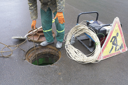 该雇员在街道上打开了舱门 以消除紧急情况 紧急事件工具安全行动工作服维修服务沥青下水道地面工人背景