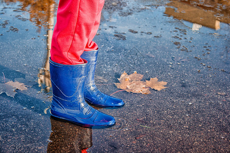 儿童雨鞋详情页小女孩的腿 在秋天的池塘里站着季节公园下雨乐趣女性反射街道孩子水坑童年背景