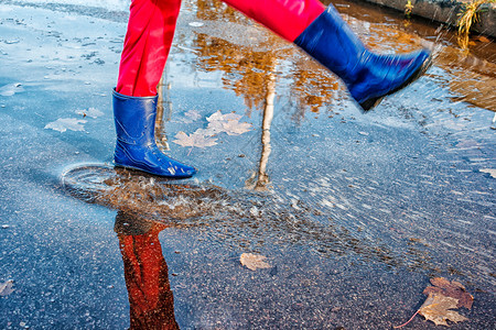 儿童雨鞋详情页女孩站在水坑里 喷水反射雨鞋水池孩子公园树叶橡皮幸福下雨乐趣背景