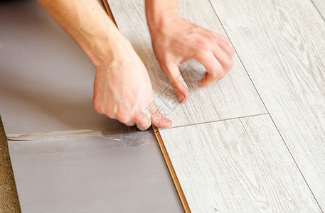 压接工具手工工的手放下压层板地板板工作服木板材料木头工具地面衬垫装修工人安装背景