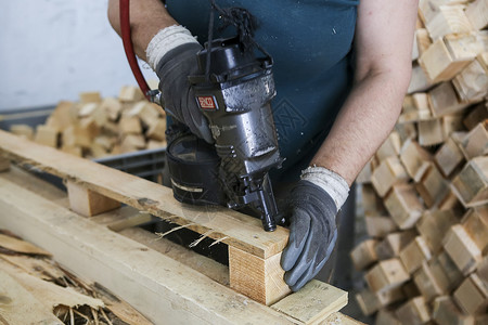 横切工匠在一个木工工厂把钉子钉在一块木头上火花工作台焊接科学构图电气男人工艺热情金属背景