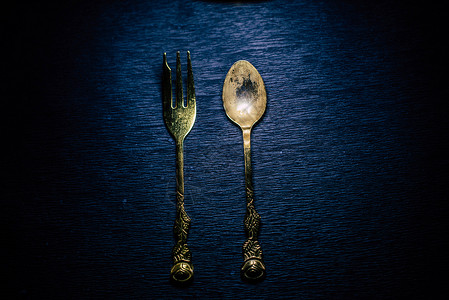 黑色背景上的经典叉子和勺子食物刀具用餐餐具菜单工具反射厨房盘子金子背景图片