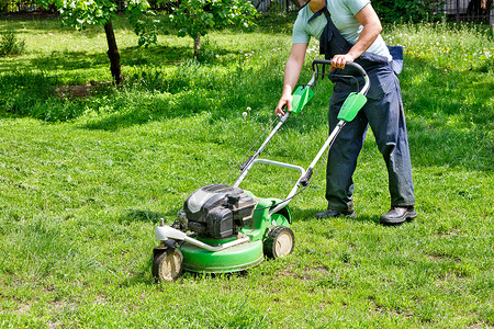 草坪修剪工人开始用汽油割草机来切草坪背景