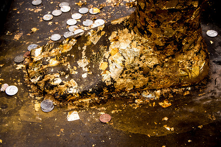 中药浴足佛足像上的金箔和泰式浴币艺术硬币金属雕像黄色文化寺庙叶子宗教背景