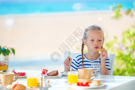 可爱的小女孩早上一大早在咖啡馆吃早餐 海景如海院子食物咖啡店面条女孩海洋盘子童年酒店午餐图片