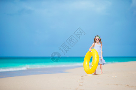 在白沙滩有充气橡皮圈的可爱女孩 准备游泳旅行海岸戒指太阳镜运动童年假期海景喜悦热带背景图片