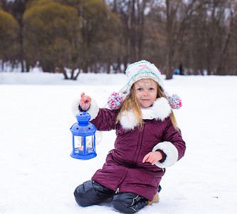 小女孩在户外灯笼里亲手点蜡烛季节女儿手套外套婴儿童年孩子蓝色天气雪花背景图片