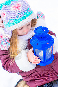 在美丽的冬季雪日 可爱的小女孩在户外守着圣诞灯笼手套蓝色女性帽子女儿晴天孩子季节雪花围巾背景图片