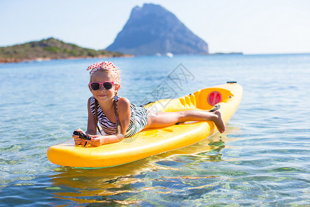 夏假期间在蓝色海中划皮艇的美丽小女孩运动小艇阳光童年晴天热带活动假期旅行天空背景图片