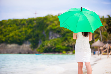 女孩拿着伞白沙滩上带绿伞的年轻女孩高度娱乐支撑海滩蓝色条纹天气旅行女士旅游背景