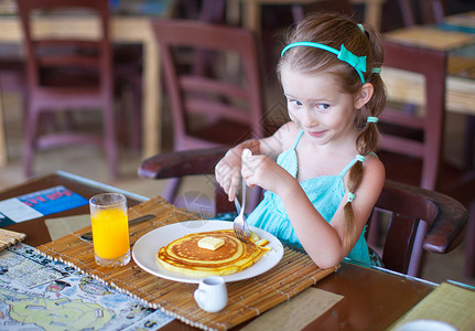 小女孩挑瓜可爱的小女孩在户外咖啡厅吃早餐快乐餐厅橙子女孩桌子蜂蜜西瓜小吃金发果汁背景