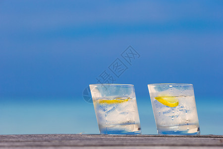 两杯水海底木木上加柠檬的水玻璃杯薄荷饮料叶子异国热带蓝色织物海滩桌子食物背景