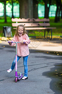 可爱的小女孩 在户外摩托车上玩得开心牛仔裤婴儿游戏童年家庭公园代步车假期水坑幸福背景图片