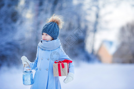 圣诞节前夕在冬冬户外的圣诞礼盒礼物可爱女孩手电筒灯笼外套围巾雪花展示享受喜悦女性闲暇背景图片