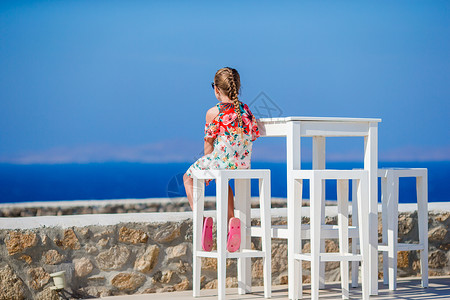 可爱的小女孩在有海景的室外咖啡馆吃早餐 该吃午饭了背景图片