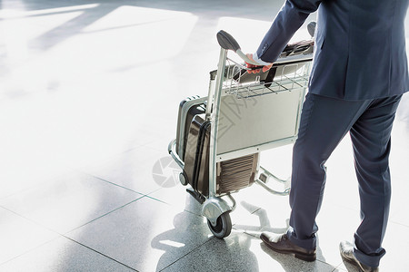 成熟的商务人士在机场将行李车推到机场报到检查职业游客成人会议飞机场商务习俗人士乘客商业背景图片