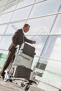 机场推车时检查时间和搬运行李的成熟商行长肖像背景图片