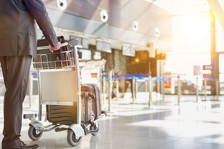成熟的商务人士在机场办理行李车托运手续 报到旅行手提箱游客入住男人检查商业飞机场套装飞机背景图片