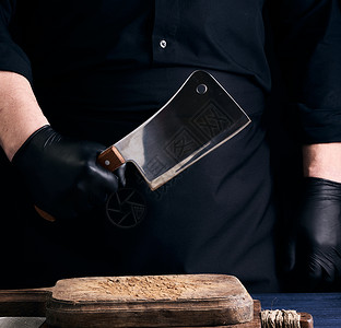 黑刀穿黑色制服和黑乳胶的男性烹饪者戴着大手套职业餐厅工具棕色木头食物男人桌子厨房木板背景