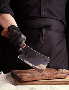 厨师拿着砧板穿黑色制服和黑乳胶的男性烹饪者戴着大手套厨师工作室男人工作厨房木头美食食物餐厅桌子背景