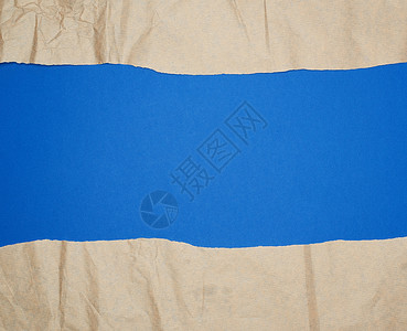 蓝色背景全帧上撕破的棕色纸边缘工艺笔记牛皮纸损害回收框架羊皮纸纸板材料背景图片