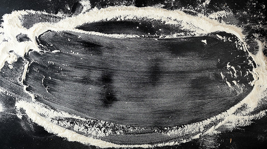 白小麦面粉散落在一张黑色的桌子上铭文框架背景图片